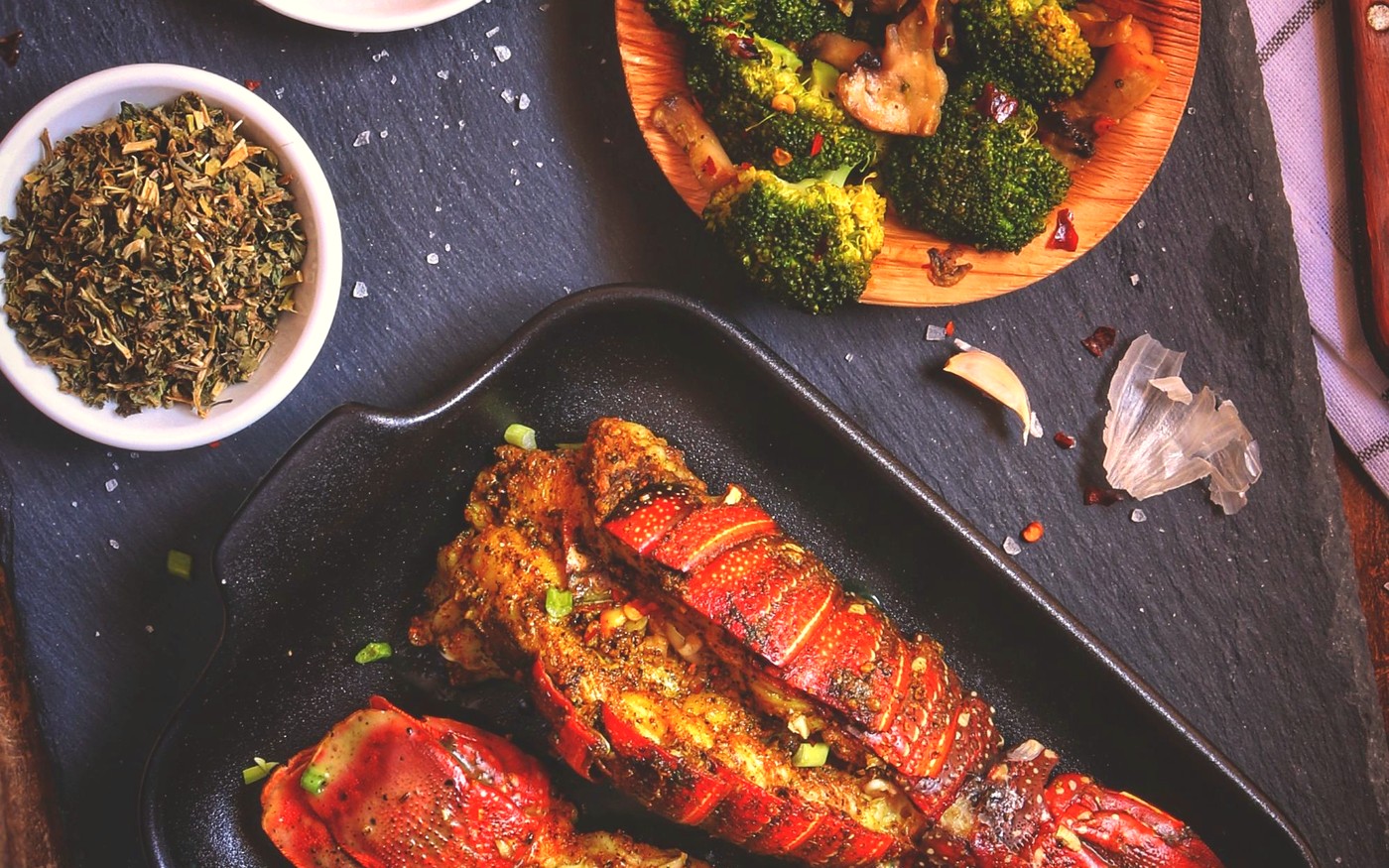 Seasoned lobster tails with bowls of spices