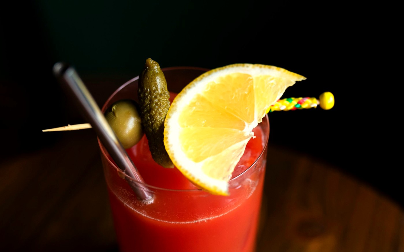 A Bloody Mary garnished on a dark bar